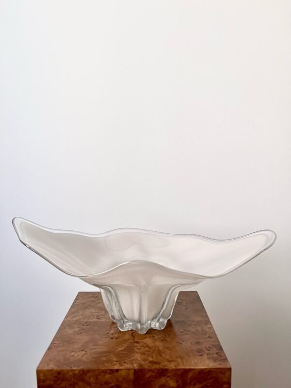 A vintage Waltherglas Susanna frosted glass bowl with a long, gently curved, petal-like shape sits on a wooden surface. The glass has a soft, diffused appearance.